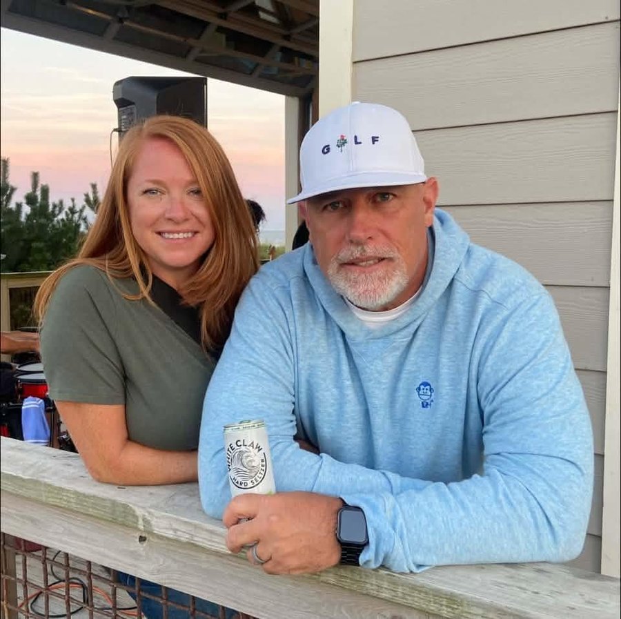Bob Merryman and his wife at the beach pavilion, Mad Monkey hoodie on